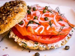 A bagel (Yiddish: ×‘×²×’×œ‎ baygl; Polish: bajgiel), also spelled beigel,[1] is a bread product originating in the Jewish communities of Poland. It is traditionally shaped by hand into the form of a ring from yeasted wheat dough, roughly hand-sized, that is first boiled for a short time in water and then baked. The result is a dense, chewy, doughy interior with a browned and sometimes crisp exterior. Bagels are often topped with seeds baked on the outer crust, with the traditional ones being poppy or sesame seeds. Some may have salt sprinkled on their surface, and there are different dough types, such as whole-grain or rye.[2][3]https://en.wikipedia.org/wiki/Bagel